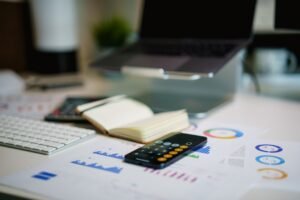 Calculatrice, documents financiers et stylo sur un bureau, pour comparer le coût d'une assistante administrative salariée et indépendante