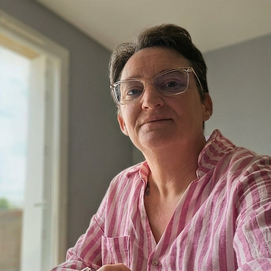 Séverine souriante à son bureau près de la fenêtre, assistante commerciale freelance au Mans