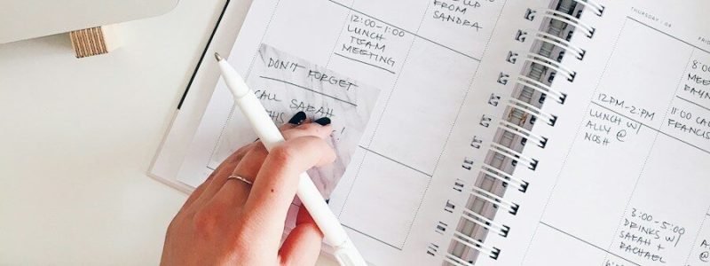 person holding notepad and pen flat lay photography
